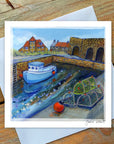Boat in a harbor at Beadnell Lime Kilns with houses and a stone wall with water at harbour.