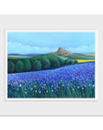 A mounted landscape painting featuring a vibrant purple lavender field in the foreground, green rolling hills and trees, and a brown mountain peak under a blue sky.