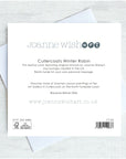 The back of a Joanne Wishart art card showing printed text ,placed on top of white envelopes on a light gray textured surface.