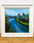 Framed painting of a scenic landscape with a river, bridge, and trees.