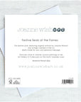 The back of a Joanne Wishart 'Festive Seals at the Farnes' greeting card, featuring product details, barcode, and text, displayed on top of a white envelope against a light gray textured background.