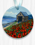 Round ornament with a painting of a Old Lifeboat station and red poppies on a white background