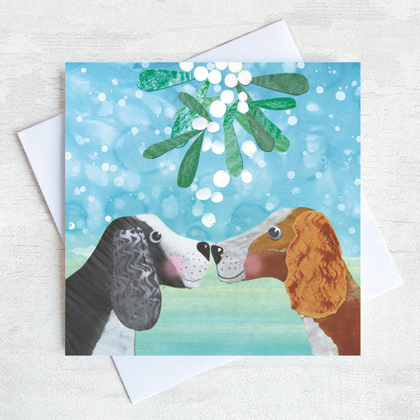 Two spaniels touch noses under the Mistletoe