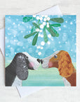 Two spaniels touch noses under the Mistletoe