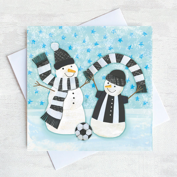Two snowmen waving black and white scarfs in the snow. A Georde themed christmas Card with bright blue stars in the sky. 