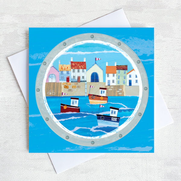 A coastal greetings card featuring a cute harbour with fishing boats on the sea.