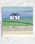 A greetings card featuring a cute scottish cottage on the landscape with a view of the sea in the distance.