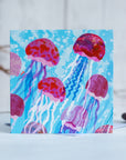 Pink and purple jelly fish swimming through the ocean.