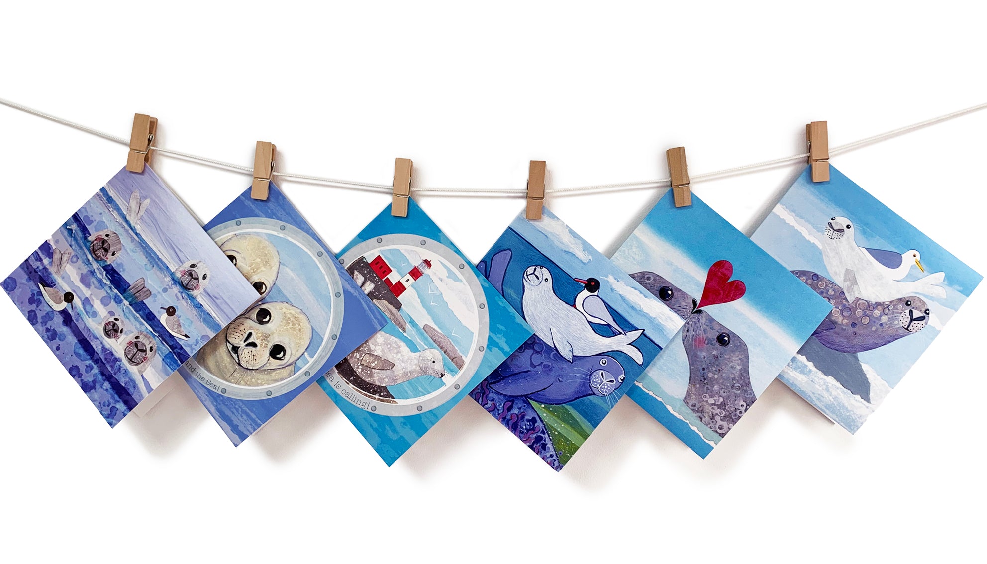 A washing line featuring a selection of greetings cards showcasing a selection of grey seal inspired designs by Joanne Wishart