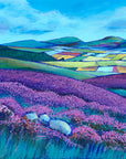 A landscape painting of the simonside hills. Swathes of purple heather are painted in the forground with a patchwork of colourful fields in the valley below. The cheviot hills can be seen in the distance with blue skies overhead.