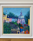 A painting in a white wood frame featuring the colourful italian village of Portmeirion.