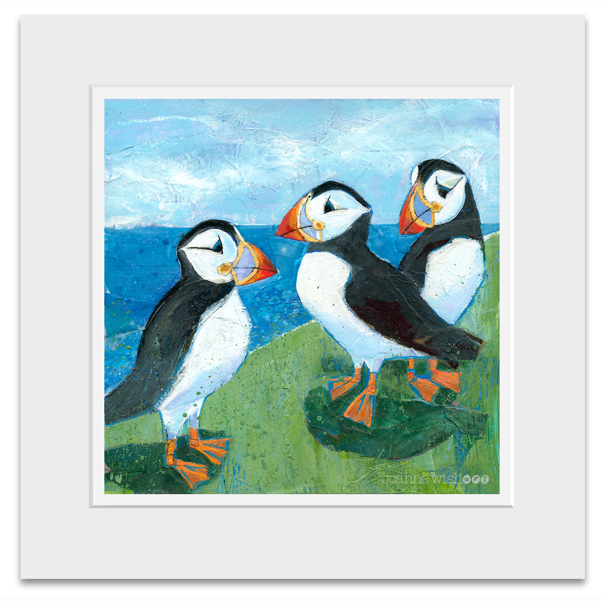 A mounted art print of three quirky puffins chatting on a grassy ledge above the north east sea.