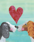 Two friendly spaniel dogs face each other blushing with a big textured red heart between them. One dog has black fur while the other has auburn. Both dogs have a white face and chest and curly haired ears. The background is textured blue and cream.