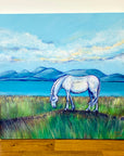 A square landscape painting of a Scottish mountain scene with a turquoise sea running across the middle of the scene. A grey pony grazes on an open grassland in the foreground.