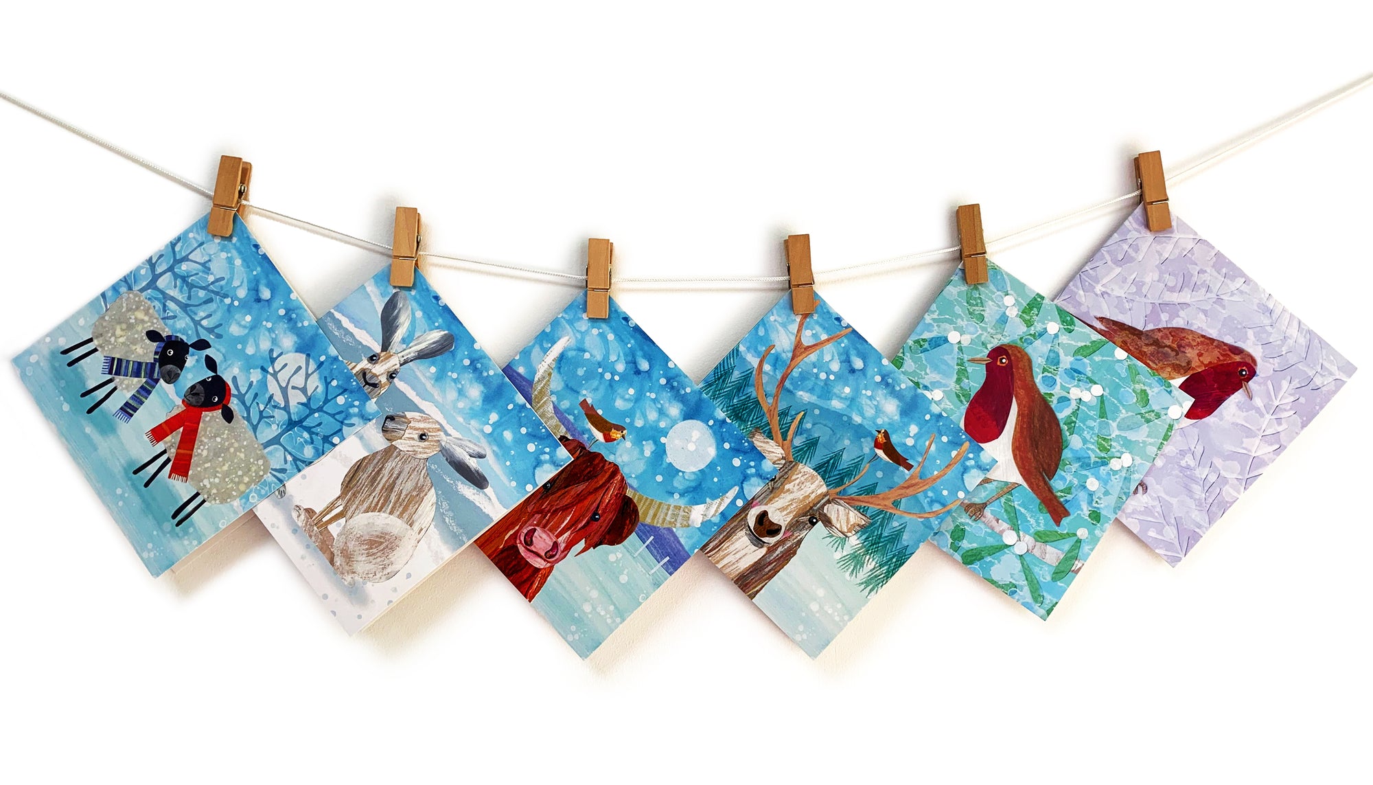 A washing line with 6 christmas cards clipped onto it. Each card features and animal in a snow storm. 