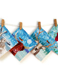 A washing line with 6 christmas cards clipped onto it. Each card features and animal in a snow storm.