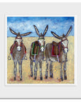 A mounted print of three cute donkeys lined up in row on the beach.