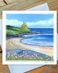 Coastal scene with a bathing house, ocean, and pink flowers in a coastal scape.