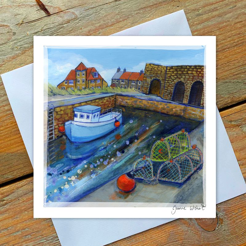 Boat in a harbor at Beadnell Lime Kilns with houses and a stone wall with water at harbour.