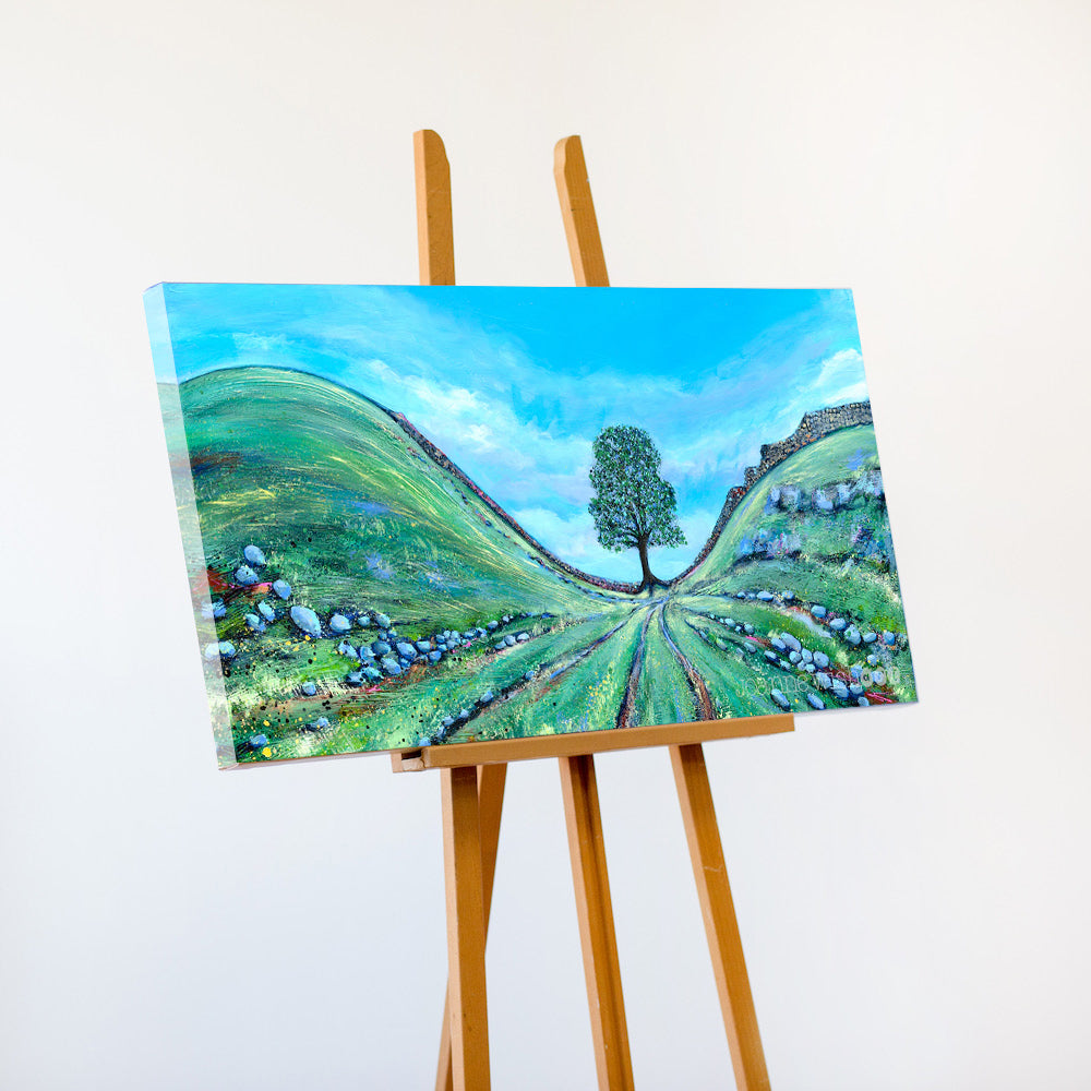 Painting of a landscape with a tree on an easel against a white background