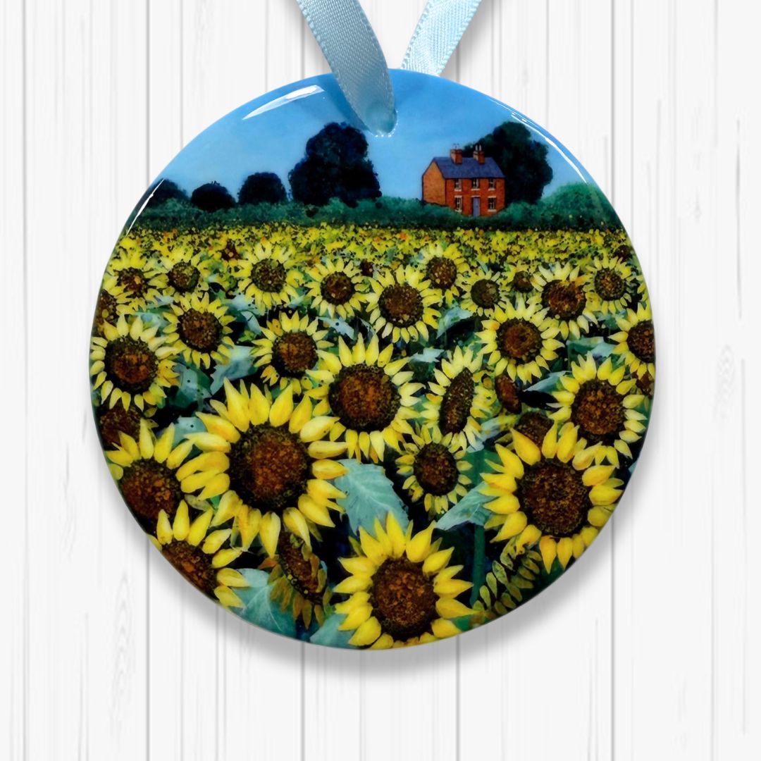 Decorative plate with sunflower field and house design on a white wooden background