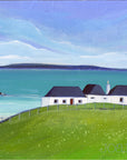 A landscape painting of a white cottage with a dark roof situated on a green grassy hill overlooking a turquoise sea and sandy beach under a cloudy blue and purple sky.