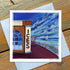 A greetings card featuring the Rendezvous Cafe with the ices signage showing on the building.There is a white lighthouse in the distance. The sky is a cloudy blue with an icy sea.  