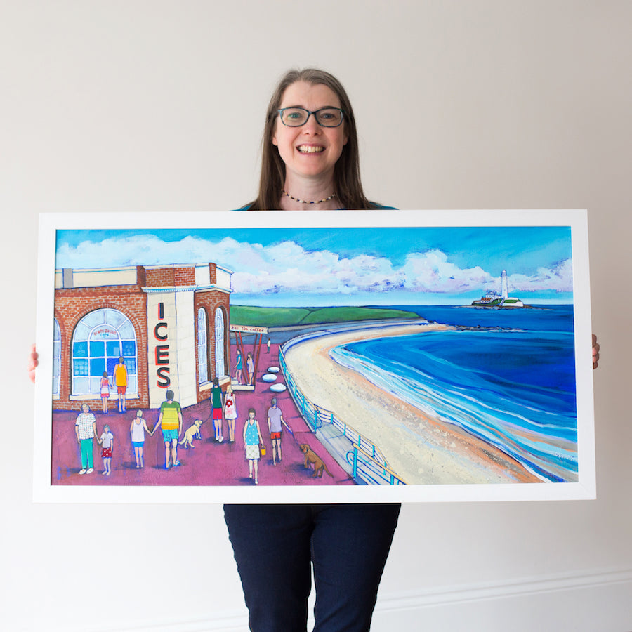 Person holding a large framed artwork of a coastal scene with people and a building labeled 'ICES'.