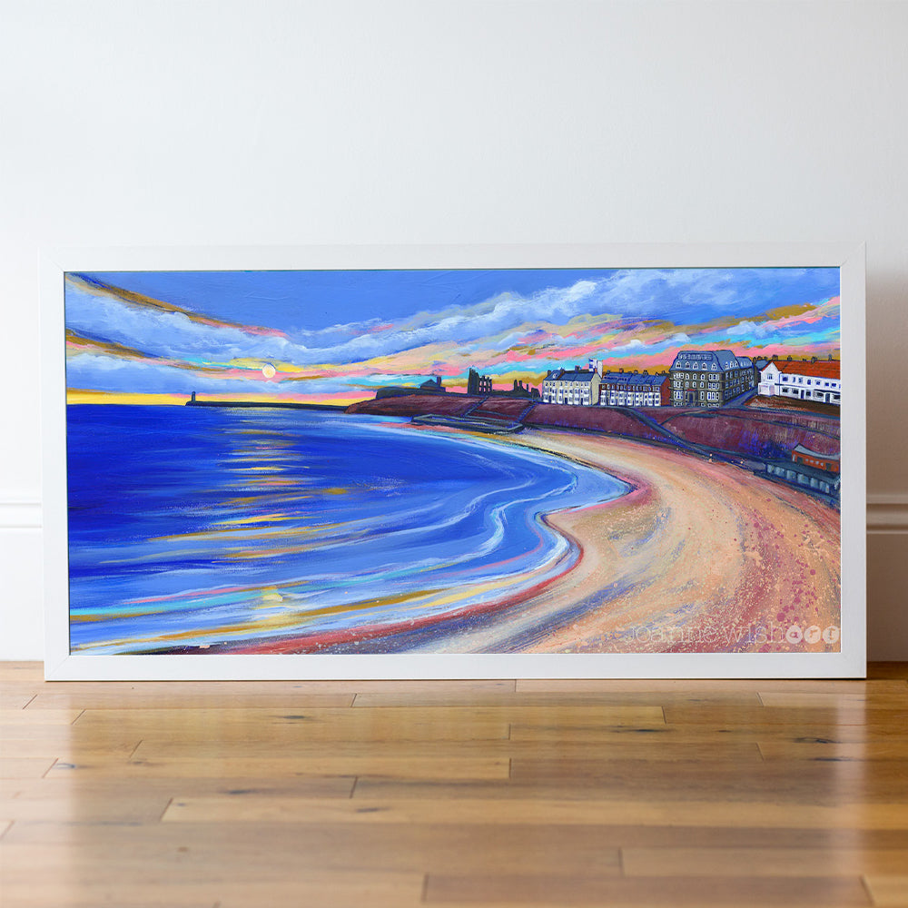 Framed painting of a winter beach scene with buildings and a colourful sky.