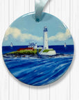 Round ceramic ornament with St Mary's lighthouse design on a white wooden background