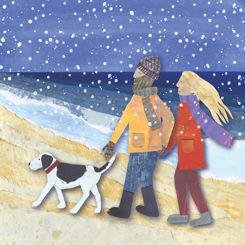 A loving vouple walk their dog on the beach during a snow flurry. They are wearing colourful long scarfs which blow in the wind behind them. 