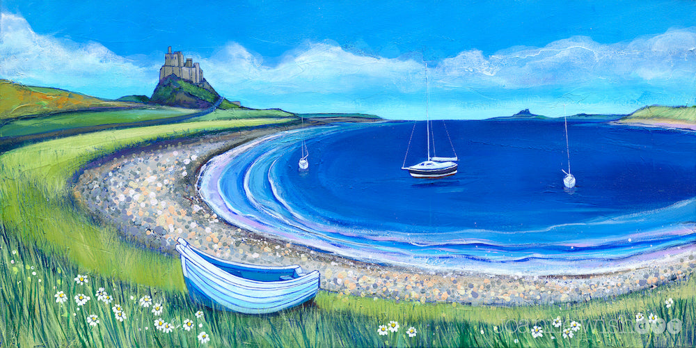Lindisfarne Castle sits proud over the bright blue sea of the bay. A sail boat bobs on the shore.  The bay is encircled by a pebbled beach and spring daisies  are scattered amongst the grasses.