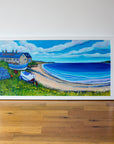 An original landscape painting of Boulmer Beach in Northumberland. Two coble fishing boats sit on the grassy shore in front of a row of old stone cottages,