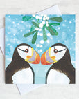 Two puffins kiss under the mistletoe. 