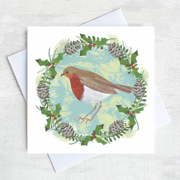 A robin with a bright red breast sits in a festive wreath of pine cones, holly and red berries. 