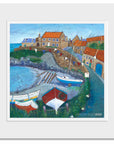 A mounted print of Craster in Northumberland featuring colourful boats and bunting in the bay.