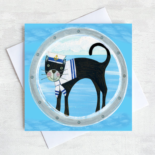 A nautical greetings card featuring a black cat in a sailor hat peeking through a ships porthole.