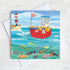 A whimsical greetings card of a fishing boat with a lighthouse  and a shoal of fish swimming in the sea.
