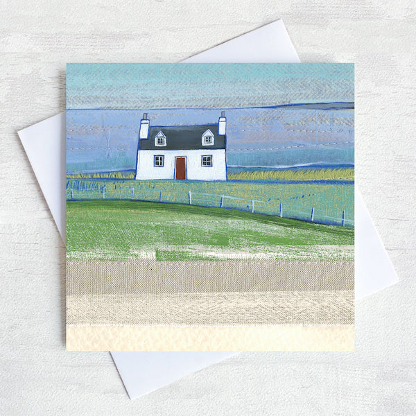 A greetings card featuring a cute scottish cottage on the landscape with a view of the sea in the distance. 