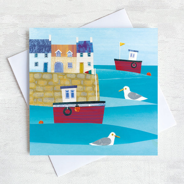 Greetings card featuring a cute harbour with red fishing boats bobbing on the sea.