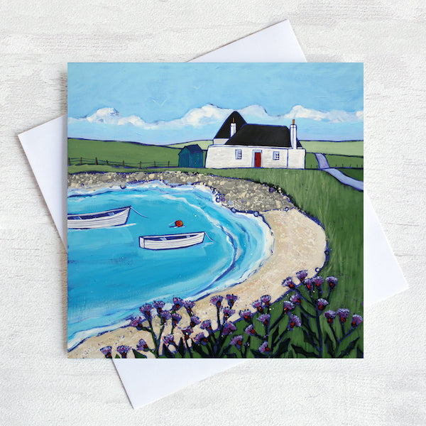 A Scottish greetings card featuring a traditional blockhouse in a sandy bay with thistles in the foreground.