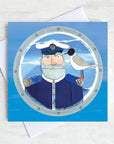 A greetings card featuring a beardy ships captain with a gull on his shoulder peeking through a porthole.