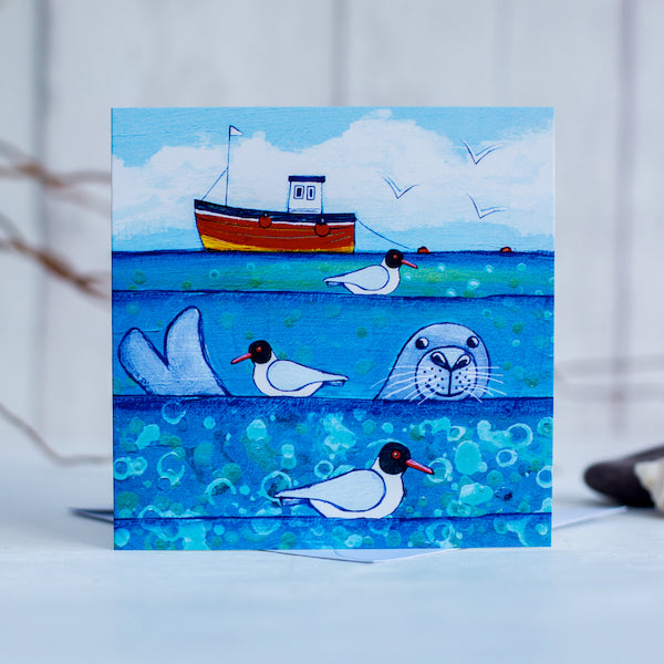 A charming greetings card from an original painting by Joanne Wishart, imaging floating on the water with these seal heads popping up above the surface to say hello!