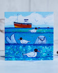 A charming greetings card from an original painting by Joanne Wishart, imaging floating on the water with these seal heads popping up above the surface to say hello!