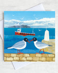 A northumberland greetings card featuring two black headed gulls on a harbour wall in front of the sea and farne islands.