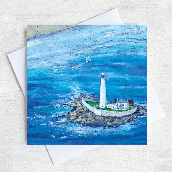 A greetings card featuring a painting of a birds eye view of St Mary's lighthouse surrounded by sea sea at high tide. 