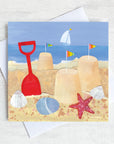 A greetings card featuring a seaside scene of sandcastles, buckets and spades.