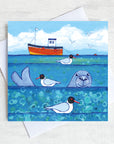 A charming greetings card from an original painting by Joanne Wishart, imaging floating on the water with these seal heads popping up above the surface to say hello!