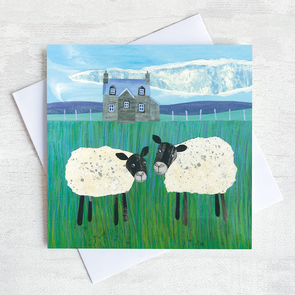 A greetings card featuring two sheep infront of a scottish stone house.