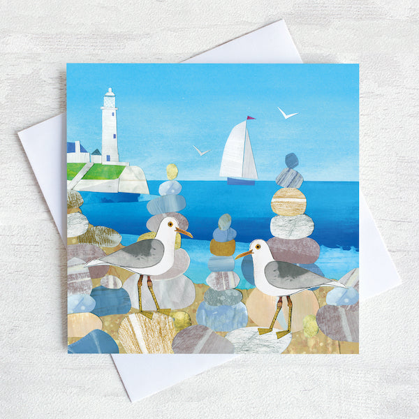 Greetings card featuring two seagulls on a beach with st mary&#39;s lighthouse in the background.